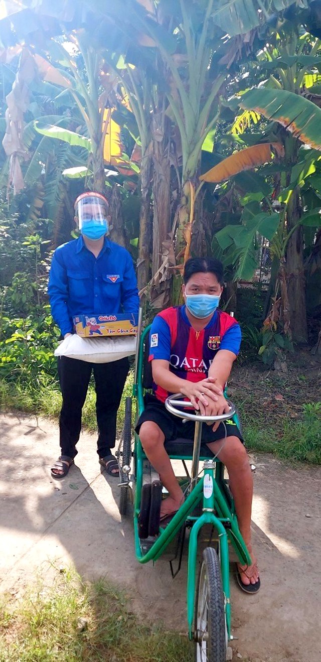  Anh Nguyễn Văn Hồ (người ngồi xe lăn) vui mừng khi nhận gạo và mì miễn phí