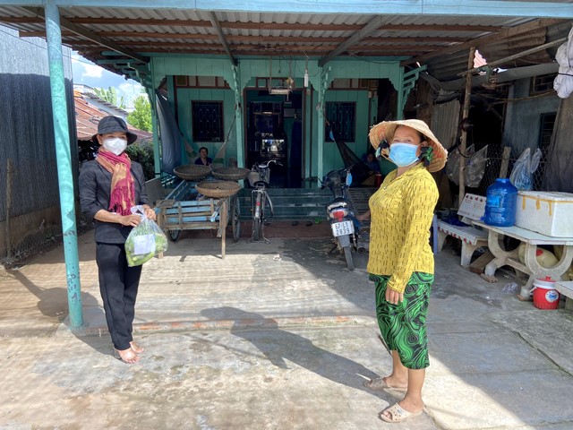 Chị Nguyễn Thị Chi (bên trái) mang những phần nhu yếu phẩm trao tận tay cho hộ nghèo tại xã Phú Thuận A