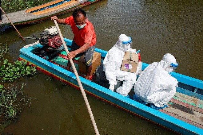 Nhân viên y tế đi thuyền tới xét nghiệm Covid-19 cho người dân gần Bangkok (Ảnh: Reuters).