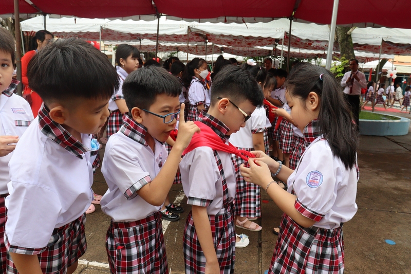 Trong phần hội, các em Trường Tiểu học Nguyễn Du vui tươi học cách thắt khăn quàng. ẢNH: CẨM HUỆ