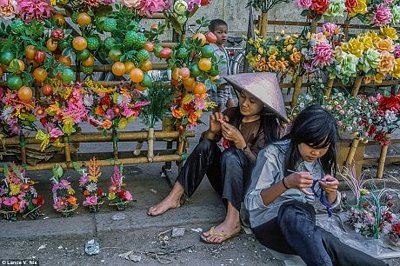 Hai cô gái ngồi bán hoa giả và trái cây bằng nhựa.