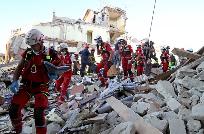 Lực lượng cứu hộ đi qua đống đổ nát ở Amatrice. (Nguồn: Daily Mail)