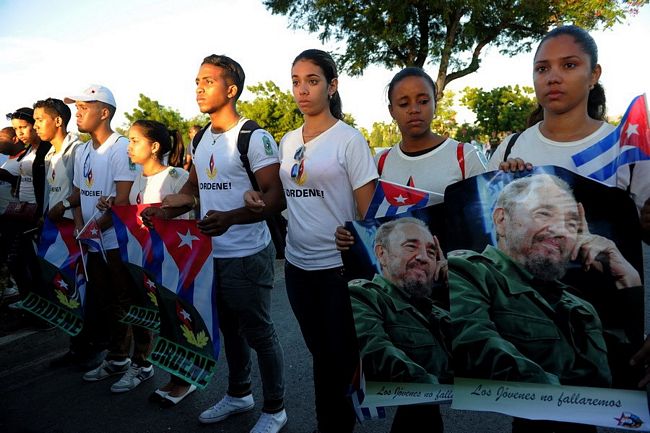 Thanh niên Cuba cầm ảnh chân dung lãnh tụ Fidel dọc tuyến đường dẫn đến nghĩa trang Santa Ifigenia. (Nguồn: AFP)
