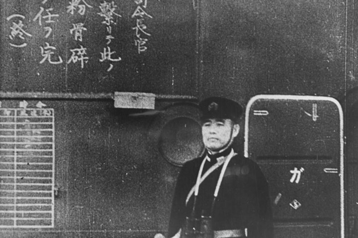 Một viên sĩ quan trên tàu sân bay Nhật Shokaku nhìn các phi cơ cất cánh. Chữ Hán Nhật bên cạnh là mệnh lệnh cho phi công.