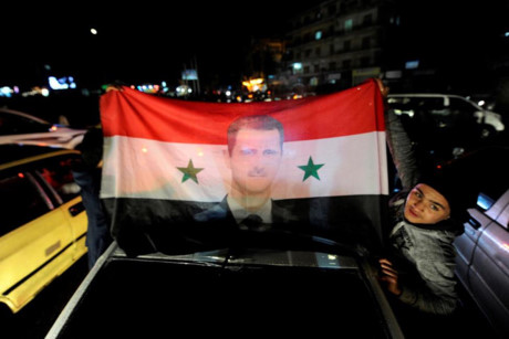 Người dân Syria mang theo cờ và ảnh của Tổng thống Bashar al-Assad để ăn mừng chiến thắng.