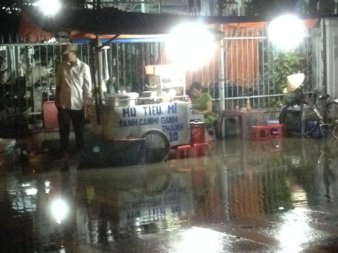 Một người bán hủ tíu gõ trên đường Mậu Thân bối rối khi bị nước “tấn công”