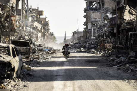 Một thanh niên ngồi xe máy để ghi hình cảnh hoang tàn ở Raqqa bằng điện thoại di động.