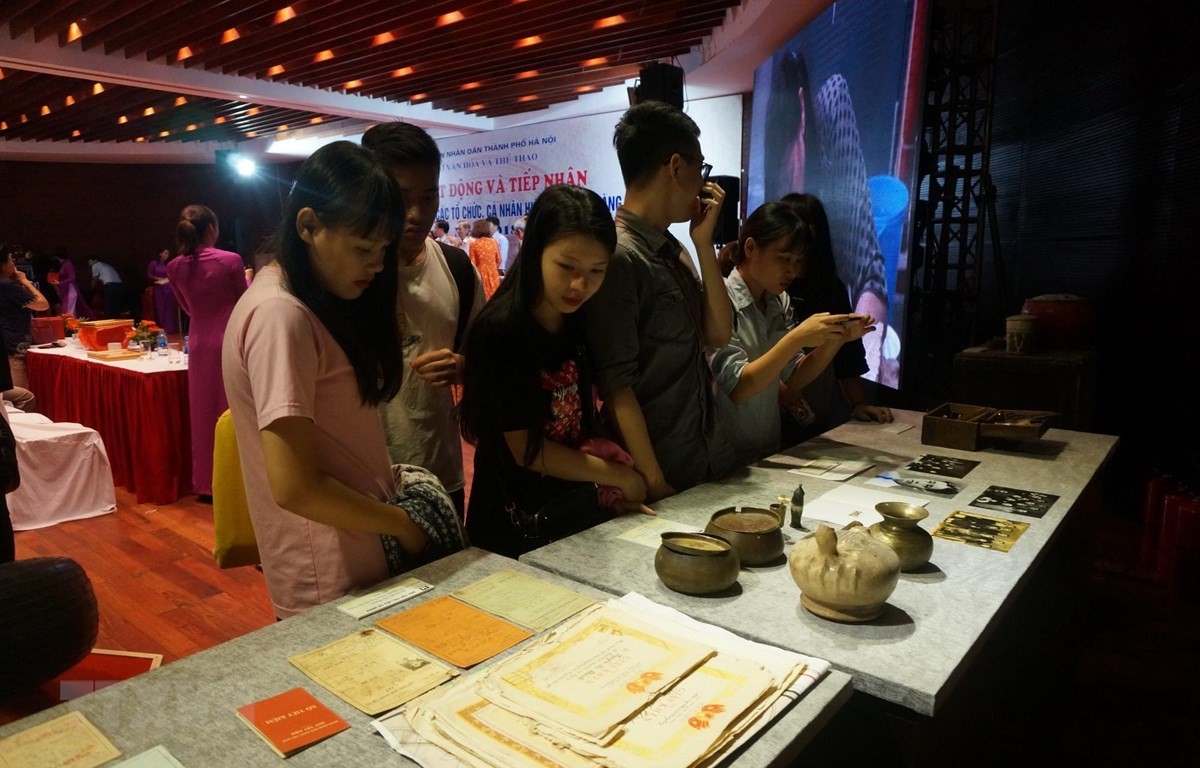 Khách tham quan tìm hiểu các tài liệu, hiện vật tại lễ tiếp nhận của Bảo tàng Hà Nội. (Ảnh: Đinh Thuận/TTXVN)