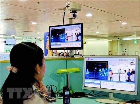 Nhân viên sân bay Tân Sơn Nhất kiểm tra màn hình hiển thị máy quét thân nhiệt đối với hành khách quốc tế đến Việt Nam. Ảnh: Đinh Hằng/TTXVN.