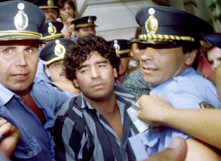  Cảnh sát hộ tống Maradona khỏi tòa án tháng 3/1994 liên quan đến cáo buộc ông bắn các nhà báo bên ngoài nhà riêng ở thành phố Mercedes. Ảnh: Reuters