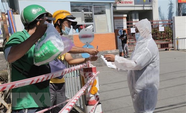 Nhân viên bệnh viện quận Tân Phú, Thành phố Hồ Chí Minh hỗ trợ giao nhận nhu yếu phẩm cho bệnh nhân khi bệnh viện bị phong tỏa. (Ảnh: TTXVN phát)
