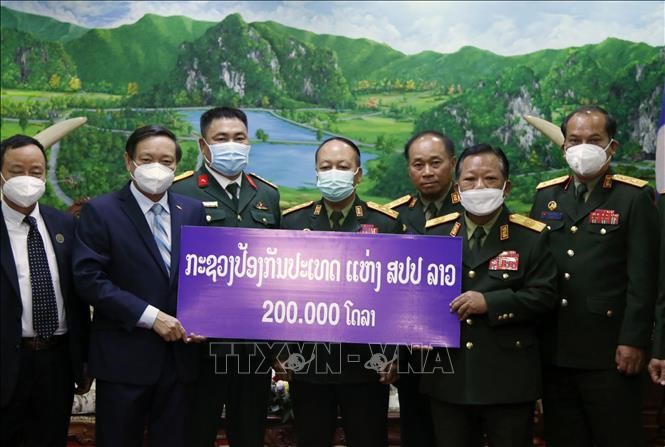 Phó Thủ tướng, Bộ trưởng Quốc phòng Lào trao số tiền 200.000 USD ủng hộ Quỹ phòng, chống COVID-19 của Việt Nam cho Đại sứ Việt Nam tại Lào Nguyễn Bá Hùng. Ảnh: Phạm Kiên