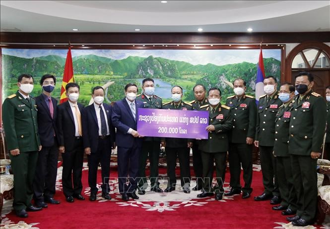 Phó Thủ tướng, Bộ trưởng Quốc phòng Lào trao số tiền 200.000 USD ủng hộ Quỹ phòng, chống COVID-19 của Việt Nam cho Đại sứ Việt Nam tại Lào Nguyễn Bá Hùng. 