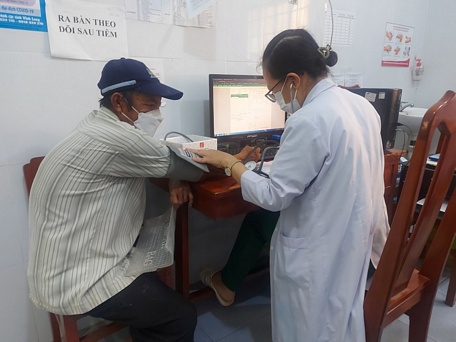 Nhân viên Trạm Y tế xã Thanh Đức (Long Hồ) đo huyết áp trước khi tiêm vắc xin ngừa COVID-19.