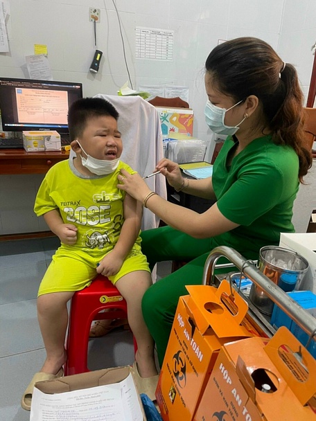 Nhân viên Trạm Y tế xã Thanh Đức- Long Hồ cùng phụ huynh dỗ dành, động viên trẻ em trước khi tiêm vắc xin ngừa COVID-19.