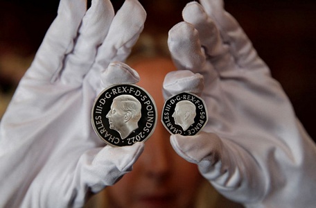 Đồng 5 bảng Anh (trái) và đồng 50 xu in chân dung Vua Charles III - Ảnh: REUTERS