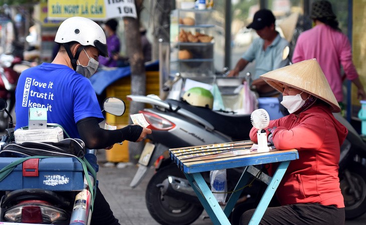 Một phụ nữ bán vé số trên đường Cách Mạng Tháng 8 (TP Biên Hòa, tỉnh Đồng Nai) dùng quạt điện để hạ nhiệt - Ảnh: A LỘC